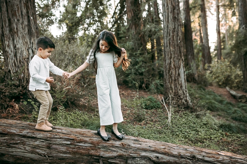a girl holding her brothers hand in the forest
